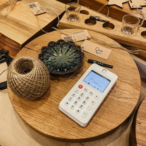 myPOS Go 2 pinapparaat op een houten tafel in een atelier naast handgemaakte producten
