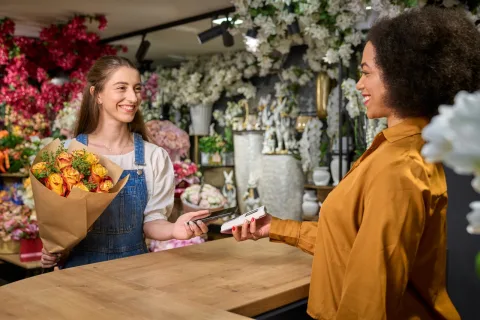 Bloemist overhandigt een boeket terwijl de klant betaalt op een myPOS Go 2 pinapparaat