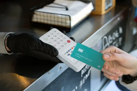 Klant houdt een bankpas bij een myPOS Go 2 pinapparaat bij een kraam met verse sappen