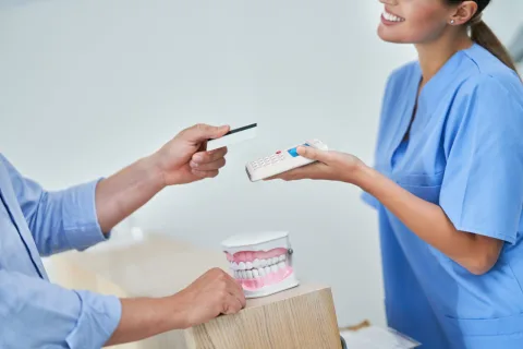Tandartsassistente laat een patiënt contactloos betalen op een myPOS Go 2 pinapparaat