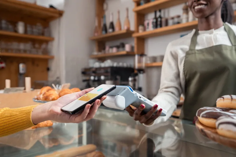 Medewerker van een koffiebar houdt een myPOS Ultra voor een klant die met haar telefoon betaalt